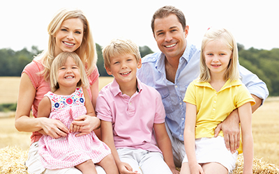 Family sitting on a straw bale in a field smiling