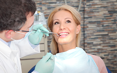 A woman visiting the dentist and having the dentist checking her teeth