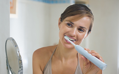 Woman brushing her teeth with an electric toothbrush