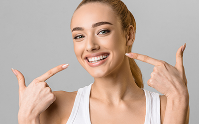 A woman smiling and pointing at her teeth